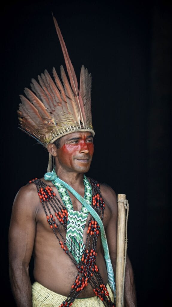 Hombre puyanawa con tocado de plumas y collares de abalorios