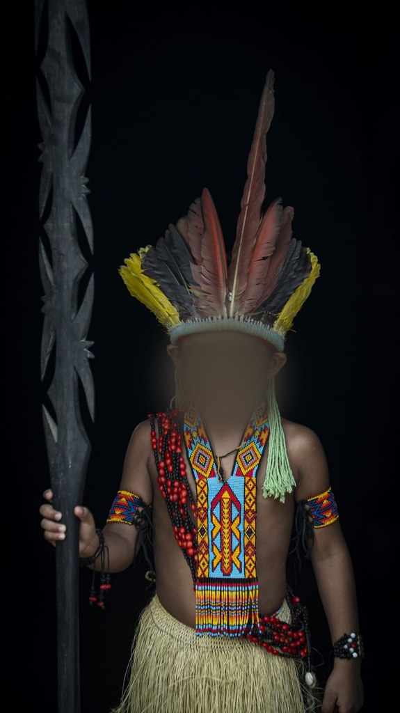 Niño puyanawa con tocado de plumas, pintura facial y adornos de abalorios