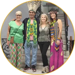 Four people, one wearing an Indigenous headdress, posing together