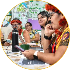 Indigenous women working with computers and mobile phones during a training session
