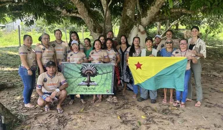 Personas de la comunidad Nukini con la pancarta de su escuela y la bandera de Acre