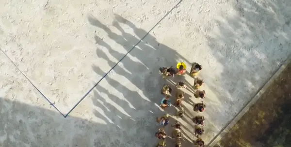Vista aérea de la comunidad Puyanawa danzando en fila en la plaza de la aldea