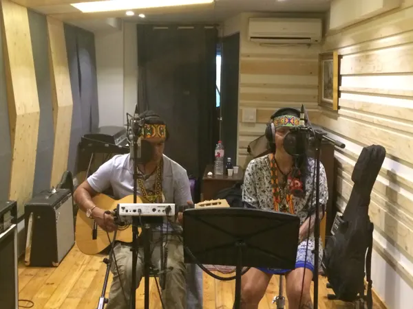 Vari sonríe con los auriculares puestos mientras Puwe toca la guitarra en el estudio