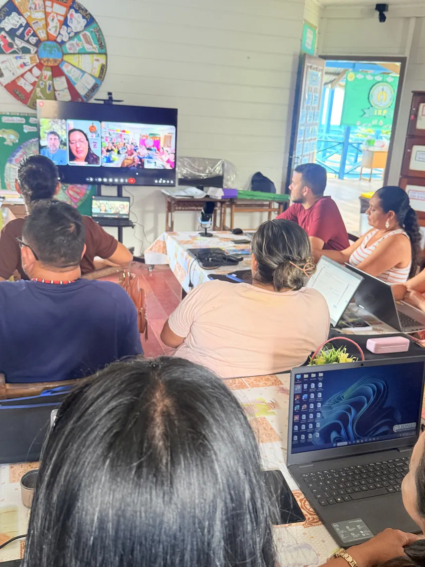 Educadors indígenes segueixen una classe per videoconferència en una pantalla gran de l'aula