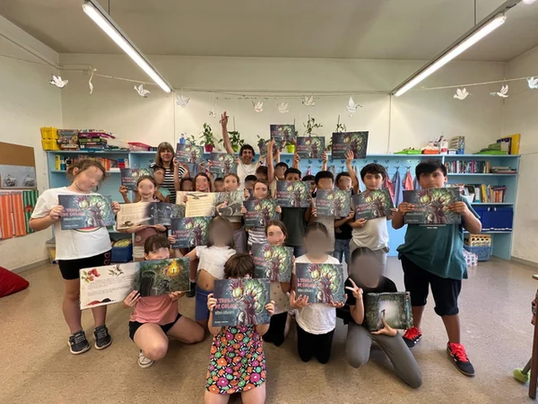 Die 3. Klasse der Escola El Palau zeigt im Klassenzimmer das Buch Els Puyanawa i l’Eruga de colors – Hêda Cêkaya