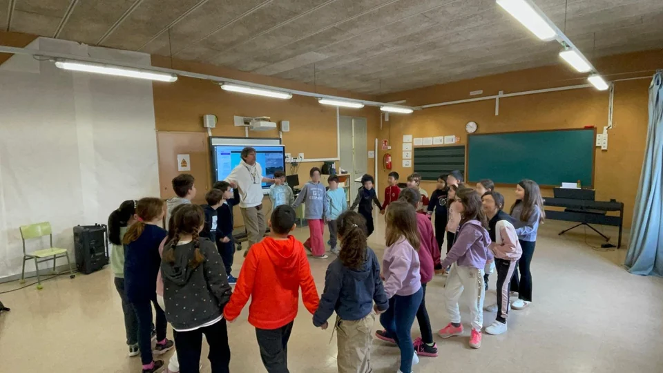 Adolf Sanz leitet im Klassenzimmer einen Kreistanz mit der 4. Klasse