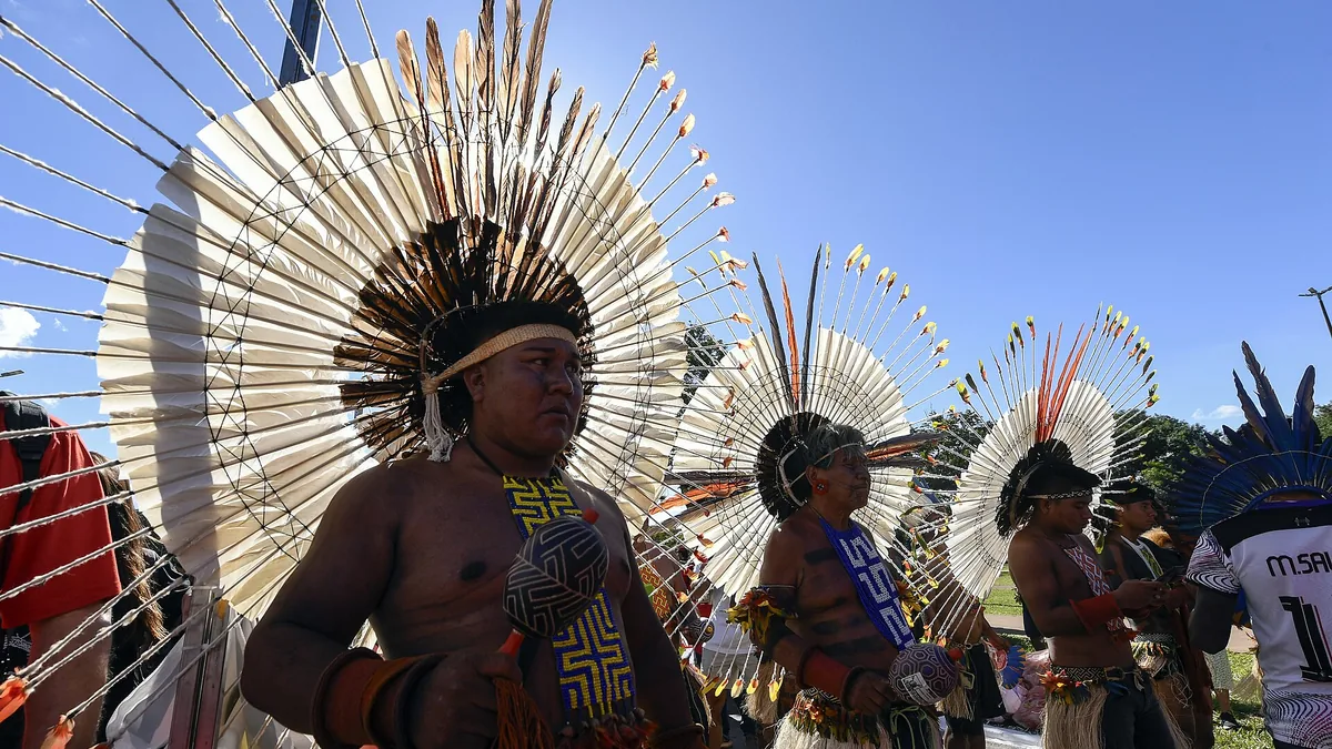 Líderes indígenas con grandes tocados de plumas blancas y rojas durante una movilización