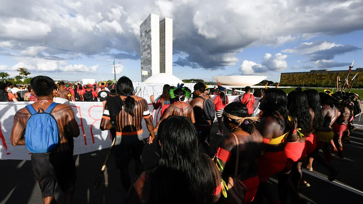 Cientos de personas indígenas caminan con pancartas hacia el Congreso Nacional de Brasil, en Brasilia