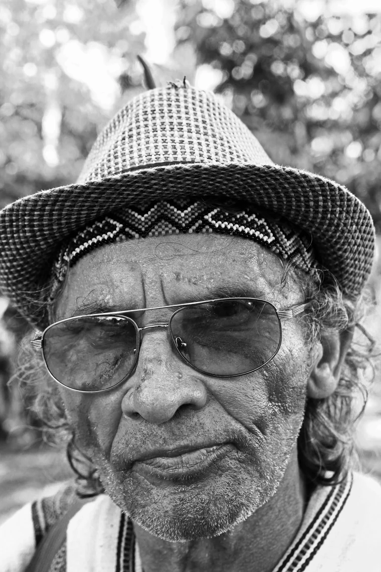 Retrato en blanco y negro de Txai Macedo, con sombrero y gafas de sol